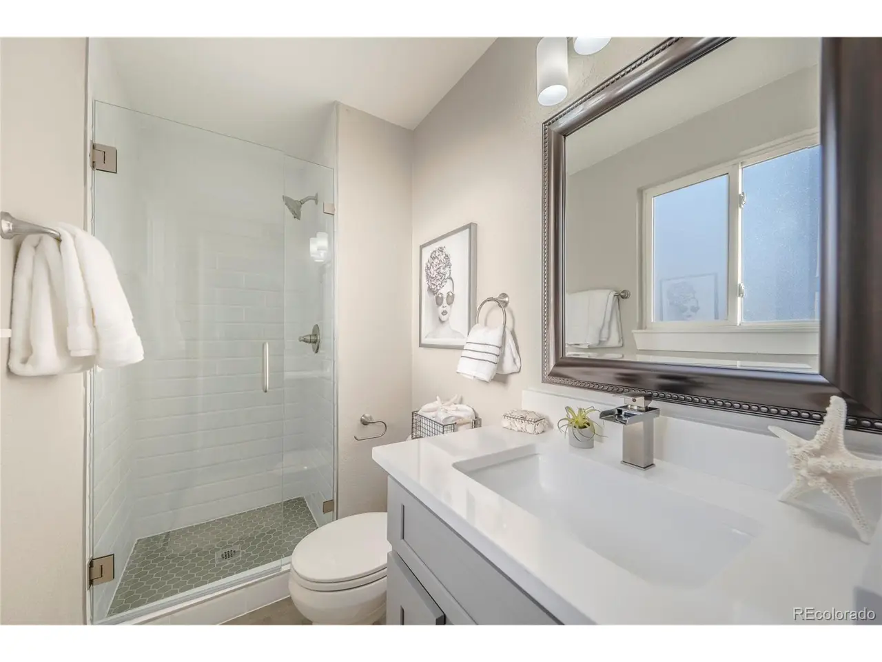 Elegant bathroom with white vanity, glass shower enclosure, and hexagonal floor tile